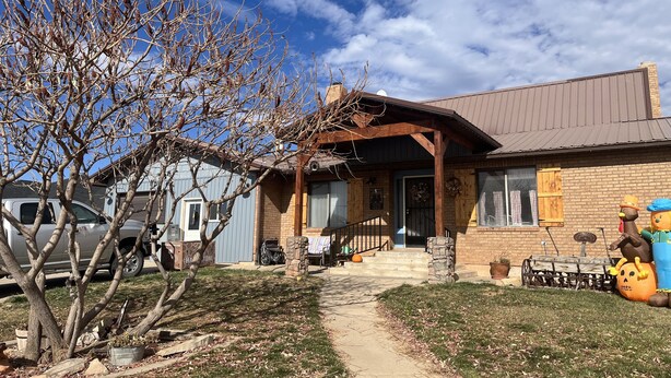 A rustic house with a porch, a garage, and a lawn. - Grandma Marva’s Hideout basecamp for many National & State Parks (Blanding)