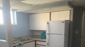 A compact kitchen with white cabinets, a refrigerator, a stove, and a sink. - Grandma Marva’s Hideout basecamp for many National & State Parks (Blanding)