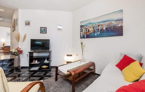 Una sala de estar moderna con una televisión de pantalla plana, un banco, una mesa de comedor y un cuadro en la pared.