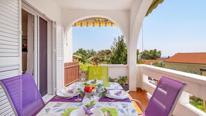 Ein Balkon mit Tisch für zwei Personen, mit Blick auf das Meer und die umliegende Vegetation.