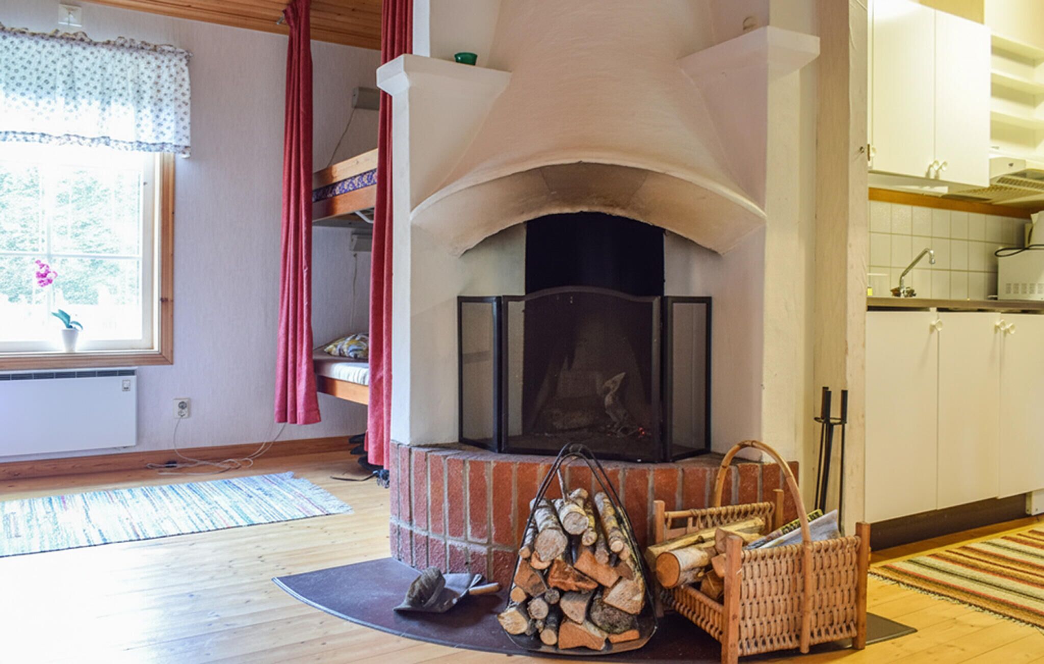 Ein Wohnzimmer mit Kamin, einem Vorhangfenster, einer Küchenzeile und Holzboden.