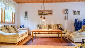A cozy living room with a sofa, two armchairs, a wooden coffee table, and a painting on the wall.