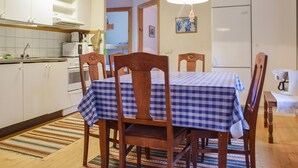 A kitchen with wooden cabinets, a table with a checkered tablecloth, and a hanging light fixture.