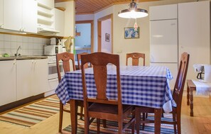 Uma cozinha com armários de madeira, uma mesa com toalha xadrez e um lustre.