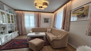 A modern living room with a beige sofa, a white coffee table, and a patterned rug. - Vacation domicile - Comfortable vacation apartment OG1 for 1-5 pers. Central. Terrace. (Bad Radkersburg)