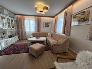 Un soggiorno moderno con un divano color beige, un tavolino da caffè bianco e un tappeto decorato.