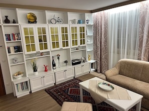 Un soggiorno con un divano, un tavolino, una libreria e un tappeto decorato.