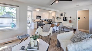 A modern kitchen with white cabinets, a microwave, and a refrigerator. There is a dining area with a white chair and a table with candles. - Hot Tub, Fire Pit: Midtown Reno Oasis! (Reno)