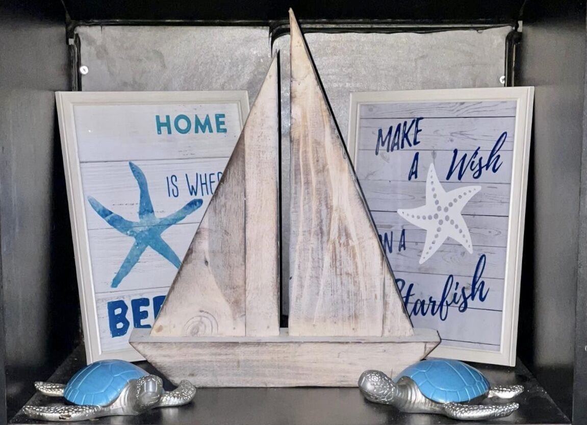 A wooden ship model between two framed signs with nautical-themed text.