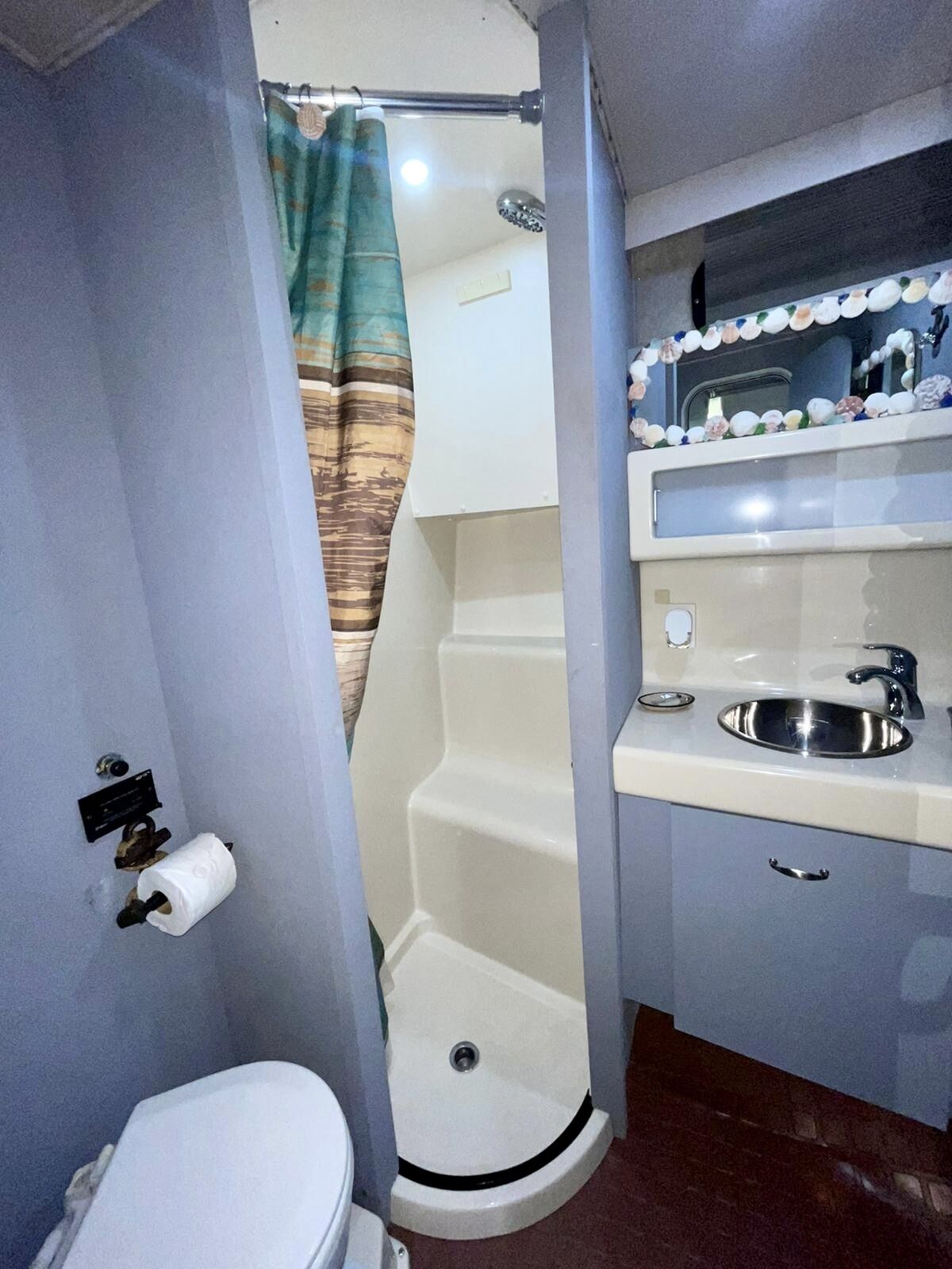 A compact bathroom with a toilet, a shower with a curtain, a sink, and a mirror above it.