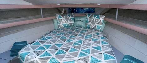 A compact bedroom with a bed, pillows, and a small shelf.