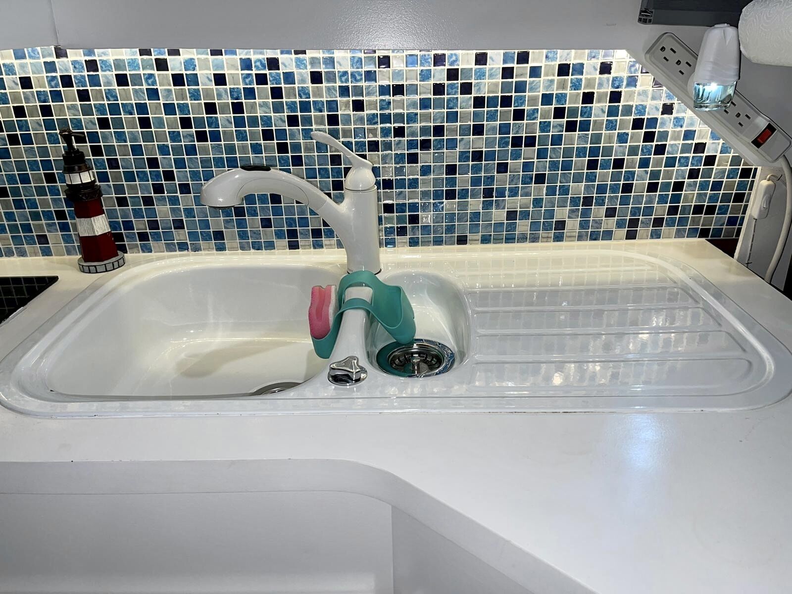 A kitchen sink with a modern faucet, a soap dispenser, and a water filter.