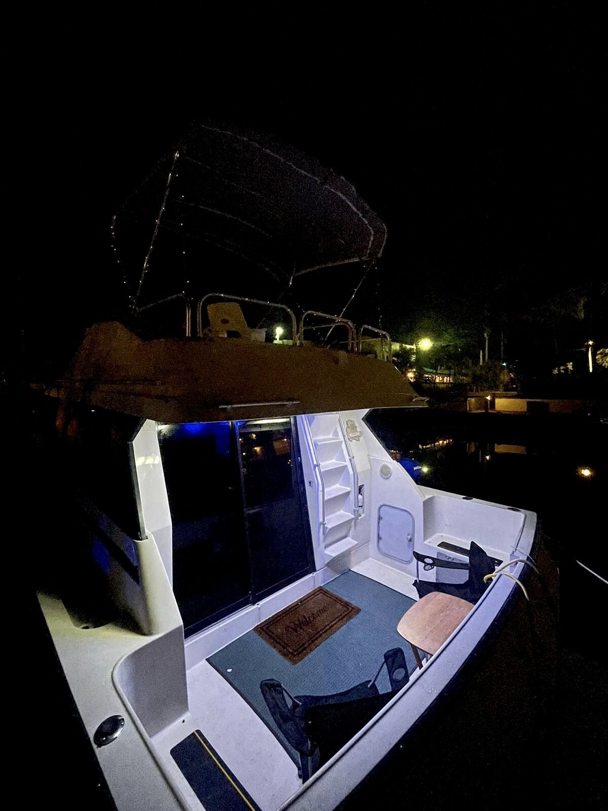 A boat with a covered deck, a seating area with a cushioned bench, and a small table.