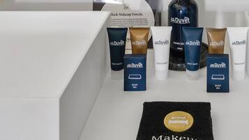 A bathroom vanity with a mirror, a black makeup towel, and various Duvet brand toiletries including body wash, soap, and conditioner.