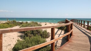 Un muelle de madera que conduce a una playa, con cielos despejados.