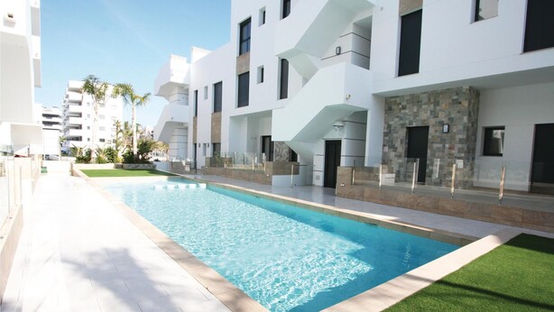 Un hotel moderno con piscina, fachada blanca y una escalera que conduce a los pisos superiores.