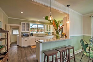 Enjoy cooking in this kitchen with a central island and stools, featuring a sink with a window above and a microwave on the countertop.