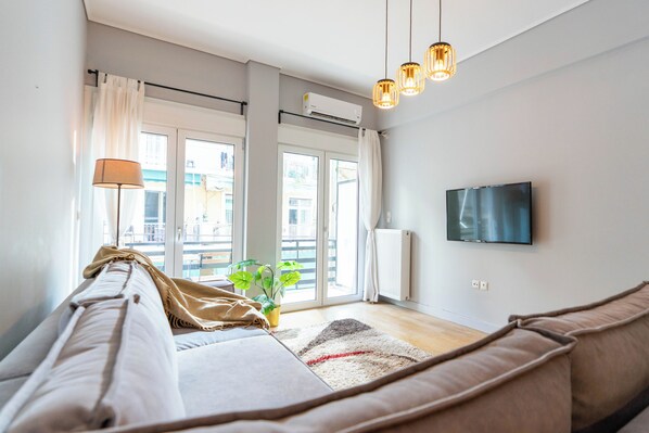 Una sala de estar moderna con un sofá, un televisor y un ventanal con cortinas.