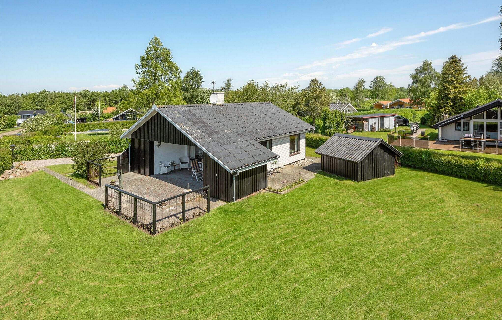Ein modernes Haus mit großer Garage, überdachter Sitzterrasse und gepflegtem Rasen.