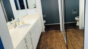 Ein Badezimmer mit Waschbecken, zwei Spiegeln, Toilette und Duschbereich.