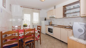 A compact kitchen with a dining table, chairs, a refrigerator, an oven, and a built-in microwave. - Awesome apartment in Pula with house sea view (Pula)