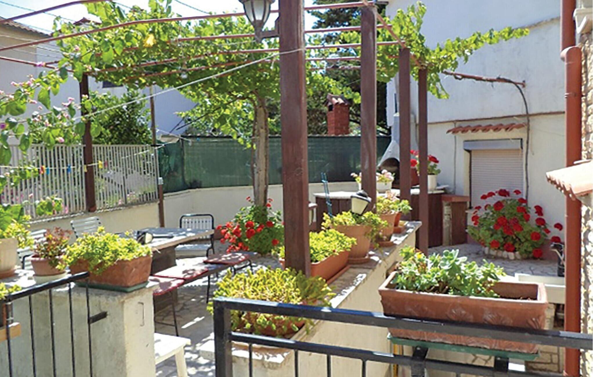 Un balcón con plantas en macetas, una mesa y sillas.