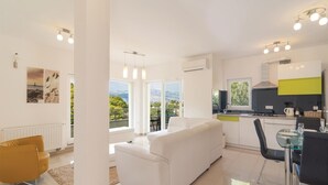 A modern kitchen with a view, a dining area, and a living room with a sofa.