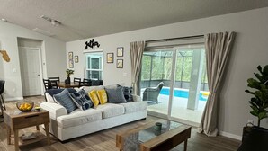 A living room with a sofa, coffee table, and a dining area with chairs and a table.