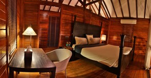 A wooden room with a bed, a table, and a chair. - Oxford Golf Resort (Pune)