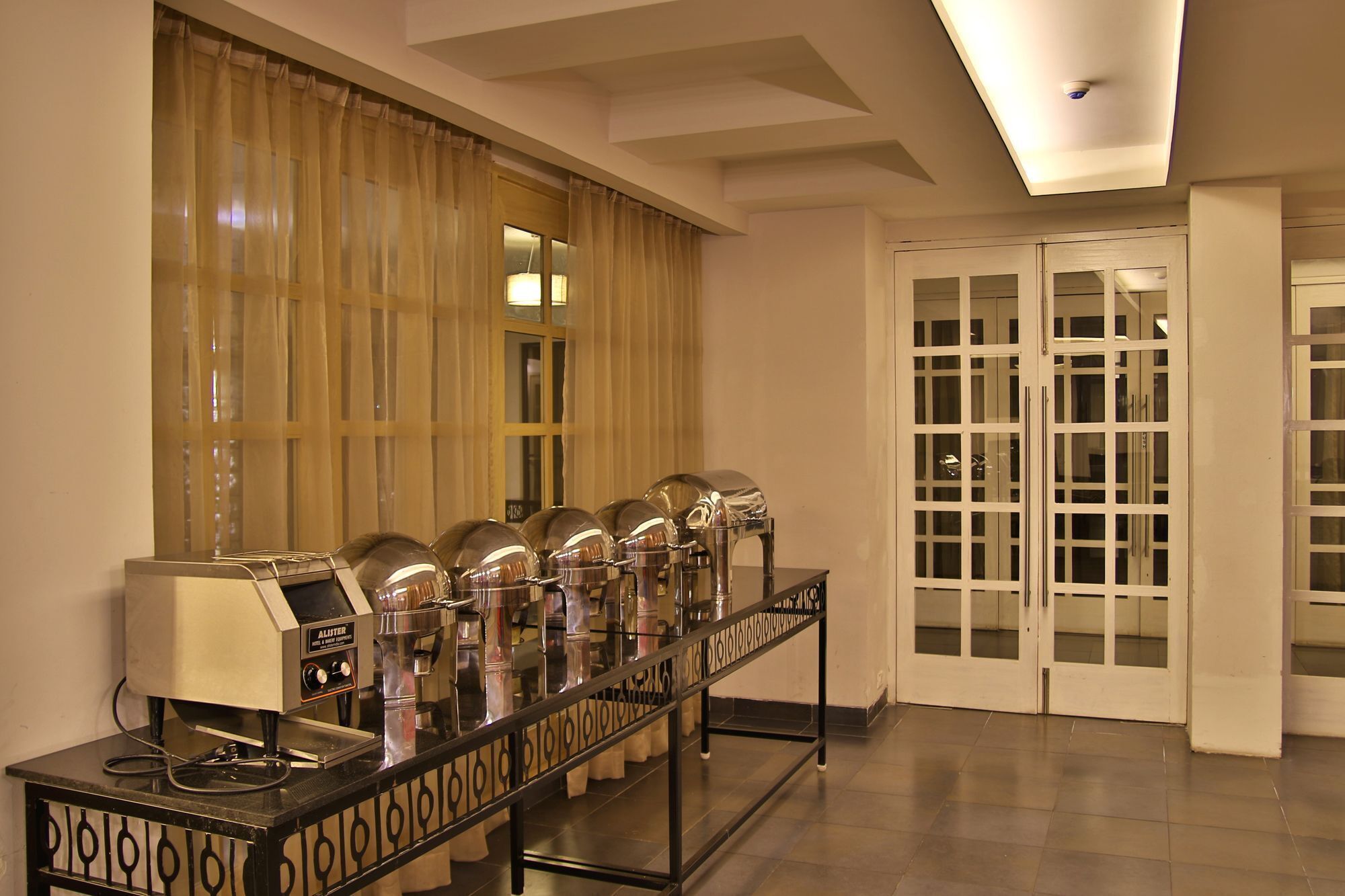 A buffet setup with multiple serving stations, a coffee machine, and a glass display case.