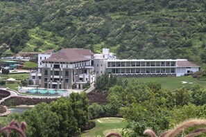 A modern hotel with a pool, a golf course, and lush greenery. - Oxford Golf Resort (Pune)