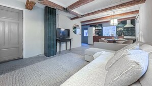 A modern living room with a sofa, TV, and kitchen in the background.