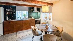 A modern kitchen with wooden cabinets, a dining table with chairs, and a hanging light fixture.
