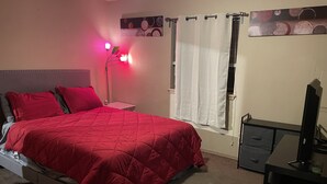 Una camera da letto con un letto, una scrivania e una finestra con tende.