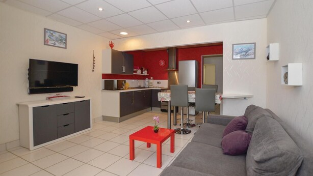 Ein modernes Wohnzimmer mit einem grauen Sofa, einem roten Couchtisch und einem Flachbildfernseher.