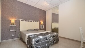 Ein Schlafzimmer mit Bett, Nachttischlampen, einem Spiegel und einer Steckdose.