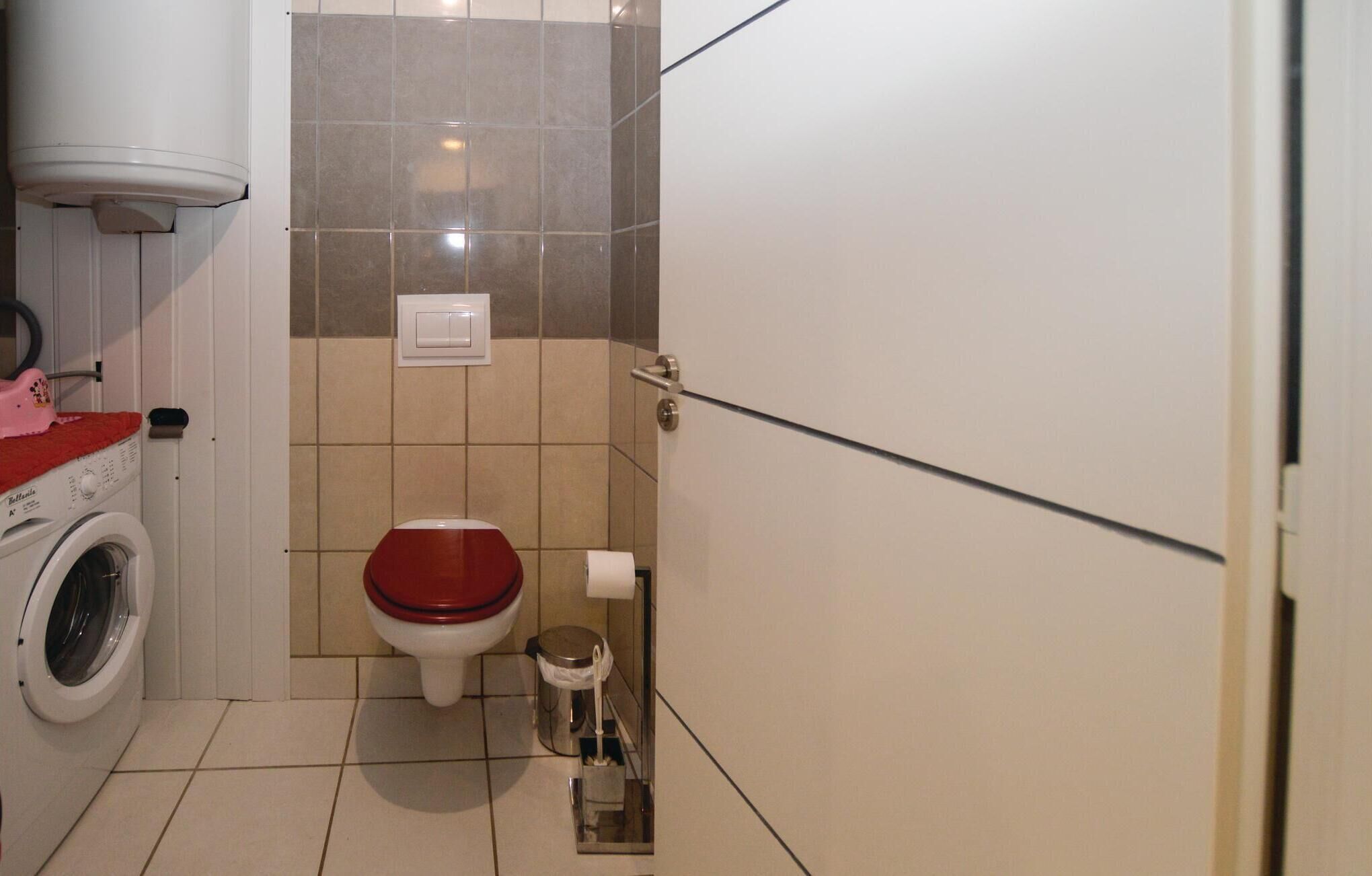 Een kleine badkamer met een wasmachine, toilet en prullenbak.