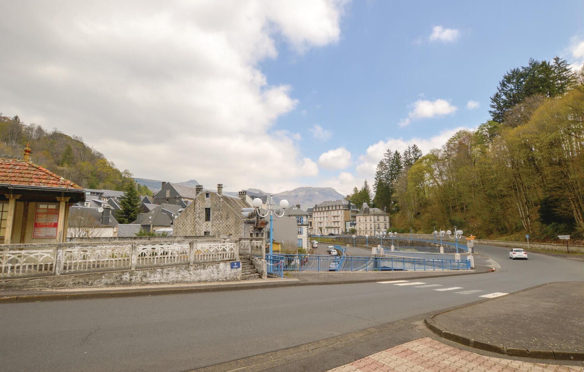 Un pueblo con edificios históricos, un puente y una montaña al fondo.