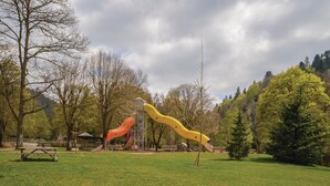 Ein Park mit Spielgeräten, Picknicktischen und einer Rasenfläche.