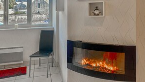Ein modernes Wohnzimmer mit Kamin, einem Sessel und Blick auf ein Gebäude.