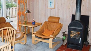 A cozy living room with a fireplace, two leather chairs, a small table with a vase of flowers, and a framed picture on the wall. - Stunning home in Middelfart with sauna (Middelfart)