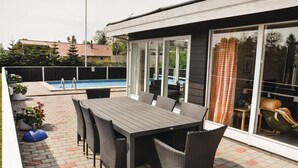 An outdoor patio with a pool, a dining table with chairs, and a sliding glass door leading to a covered area. - Stunning home in Middelfart with sauna (Middelfart)