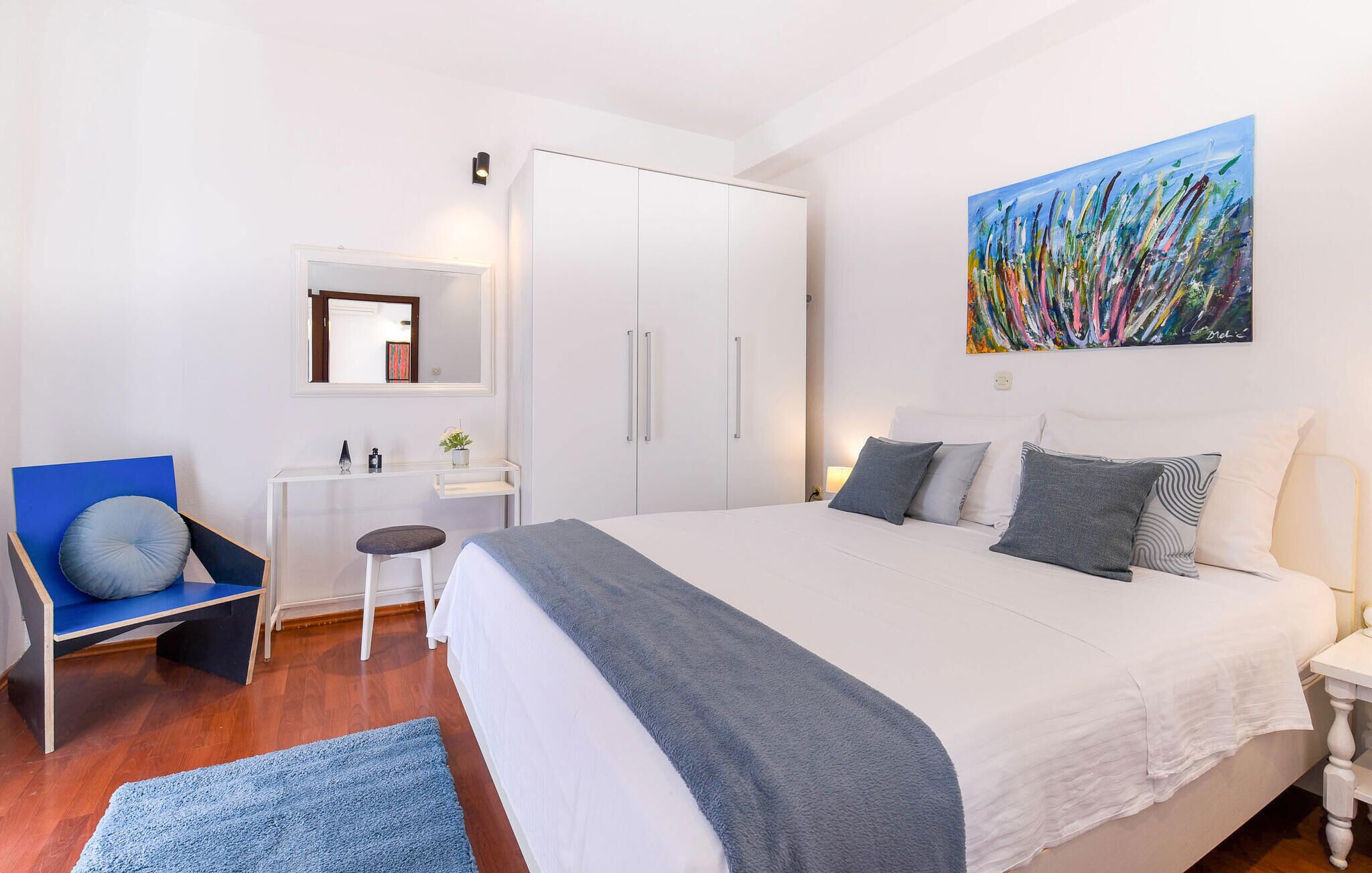 A bedroom with a large bed, a desk, a chair, and a wardrobe.