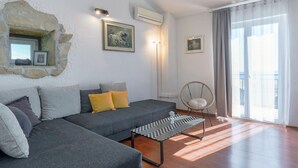 A modern living room with a grey sofa, a patterned coffee table, and a stone wall. - Awesome home in Podstrana (Podstrana)