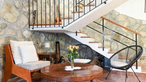 A cozy living area with a wooden coffee table, two chairs, a vase of flowers, and a staircase with a stone wall backdrop. - Awesome home in Podstrana (Podstrana)