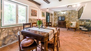 A dining area with a stone wall, wooden furniture, and a television. - Awesome home in Podstrana (Podstrana)