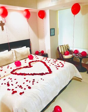 A hotel room with a bed, a cross on the wall, and red balloons.
