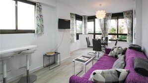 A modern living room with a purple sofa, a dining table, and a TV mounted on the wall. - Cozy apartment in Torrevieja with house sea view (Torrevieja)