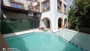 Un bâtiment moderne doté d’une piscine, de grandes fenêtres et d’un balcon.