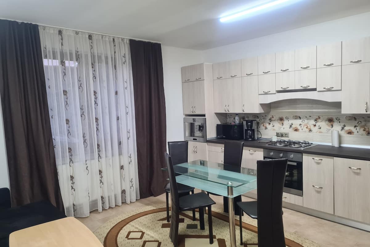 A compact kitchen with a dining table, chairs, and a stove.